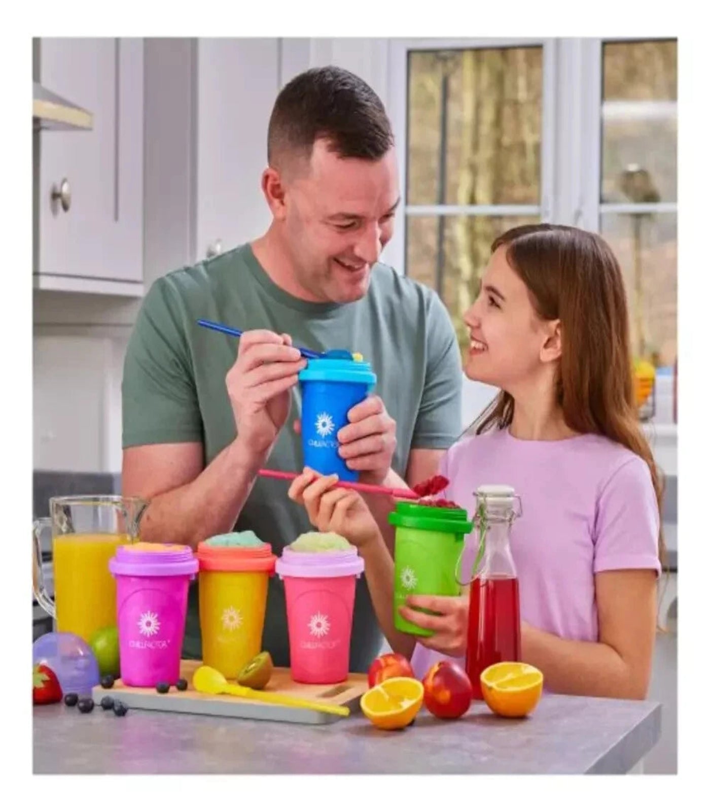 Man and young girl in a kitchen with colorful smoothie cups and juice bottles.