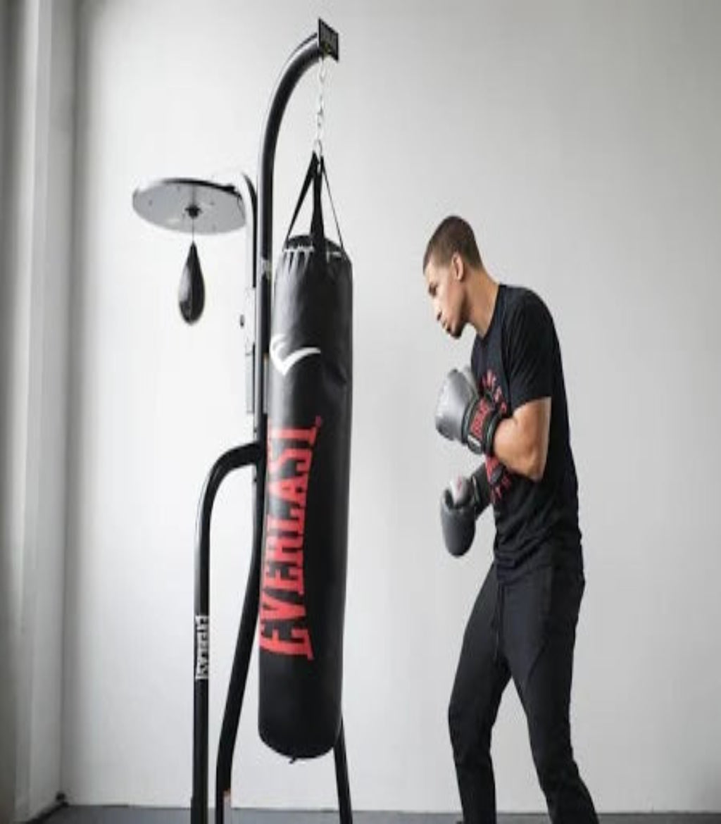 Person wearing boxing gloves and punching a Everlast punching bag in a gym setting.