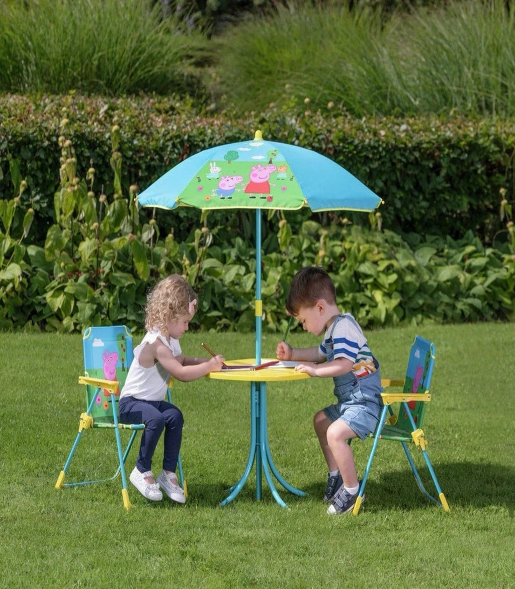 Two children sitting at a colorful outdoor table with chairs and a matching umbrella in a garden setting.