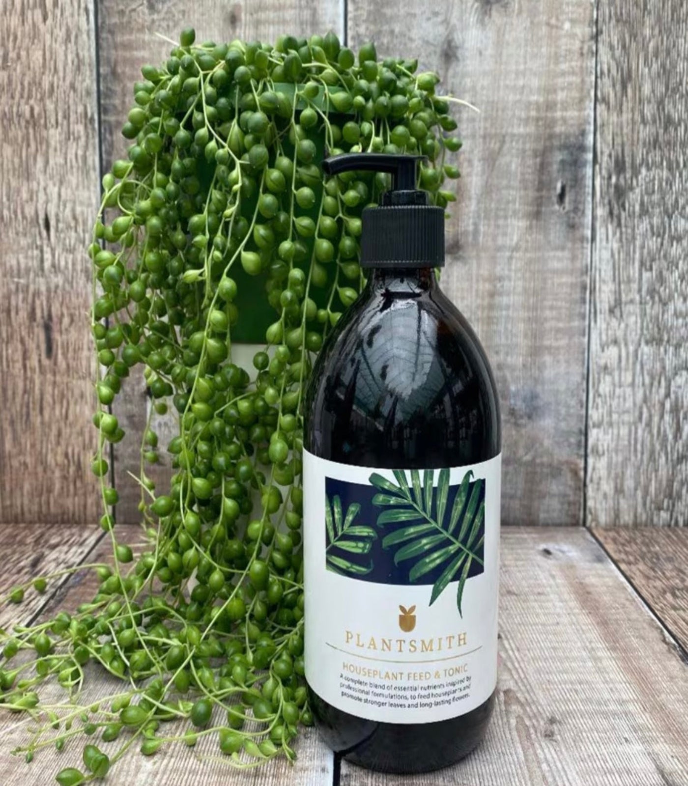 Bottle of Plantsmith product with a label featuring green leaves on a wooden surface with a plant.