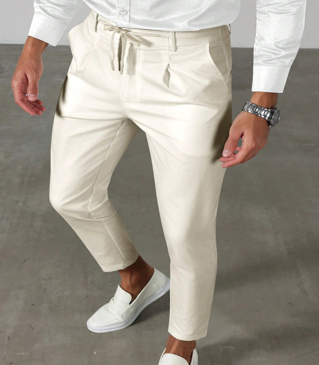 Person wearing white shirt, beige pants, and white shoes on a gray floor.