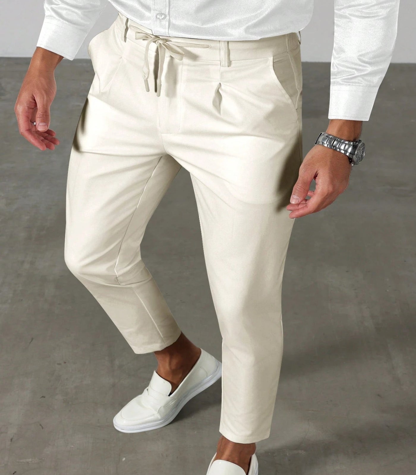 Person wearing white shirt, beige pants, and white shoes on a gray floor.
