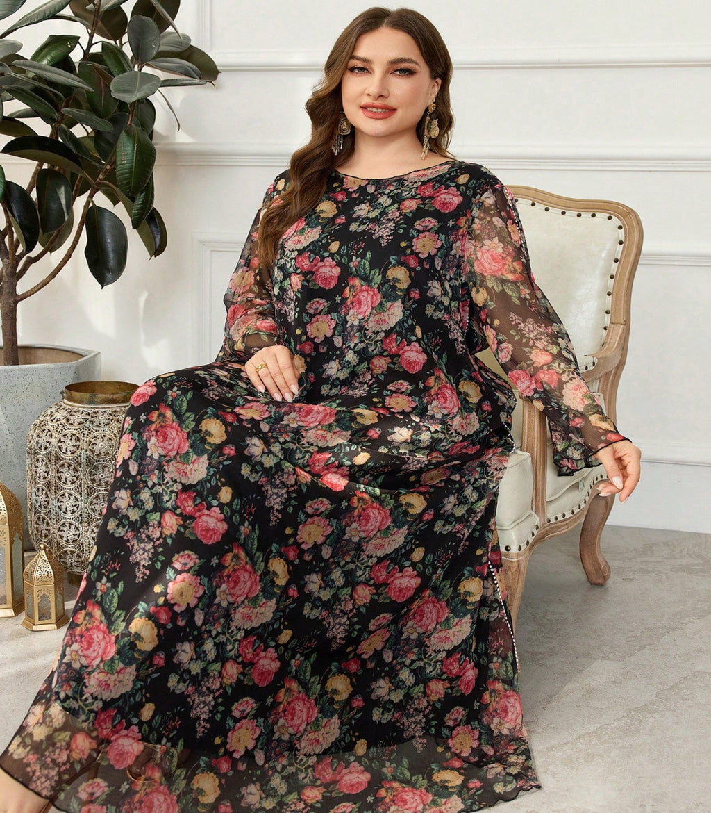 Woman wearing a floral dress sitting on a chair in a room with a plant and decorative items.