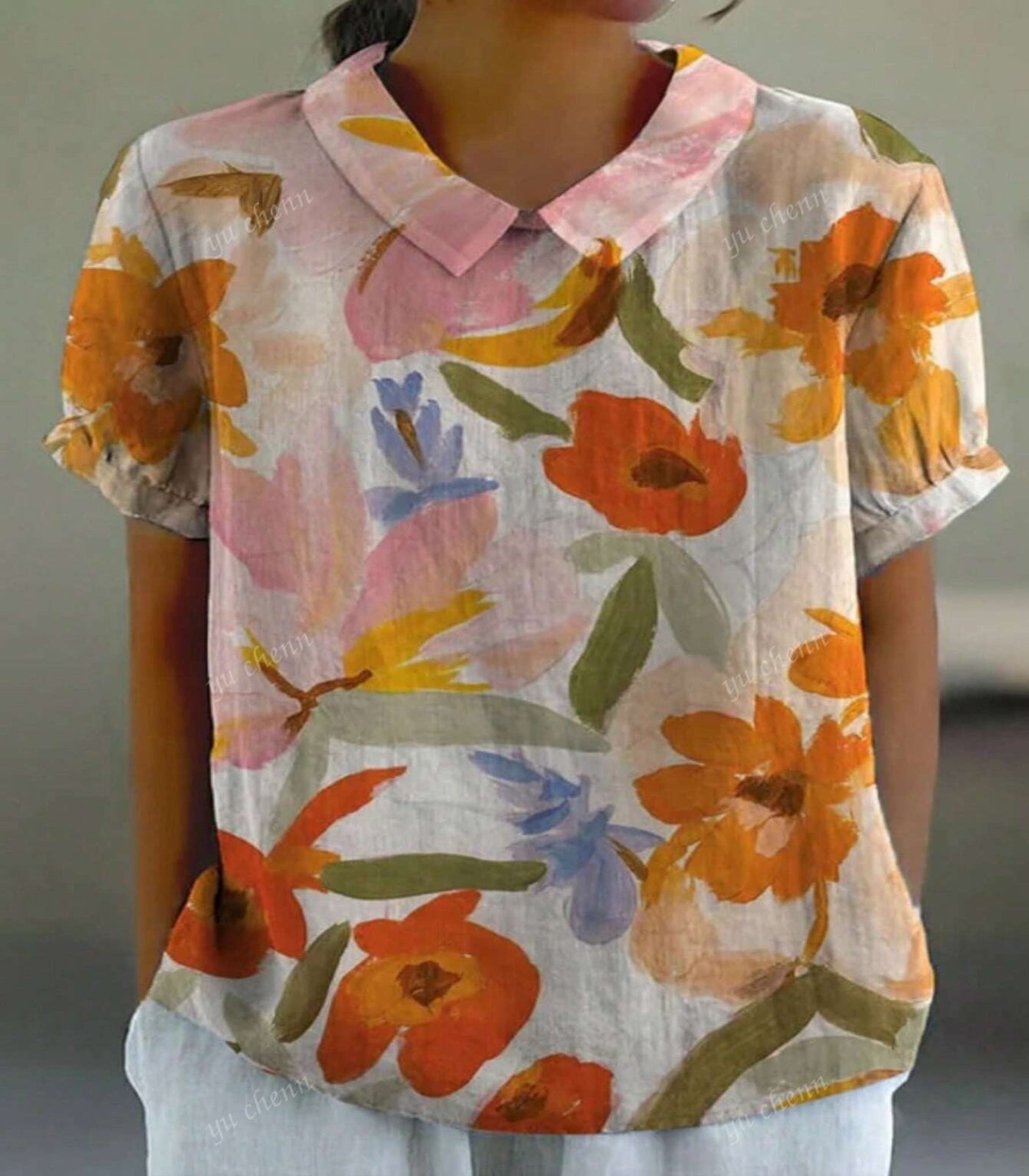 Person wearing a floral blouse with orange and pink flowers on a blurred background