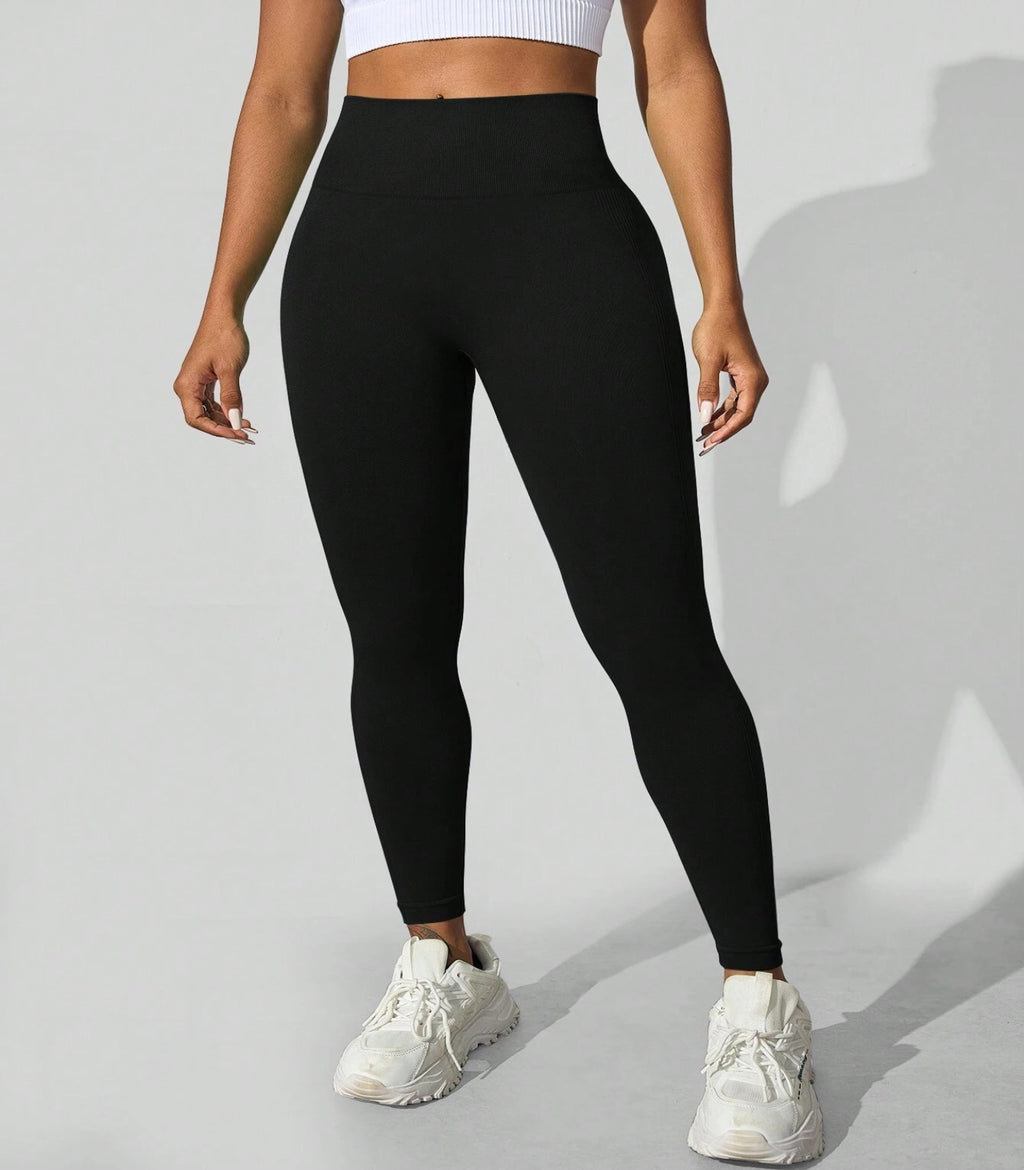 Person wearing black leggings and white sneakers on a light gray background