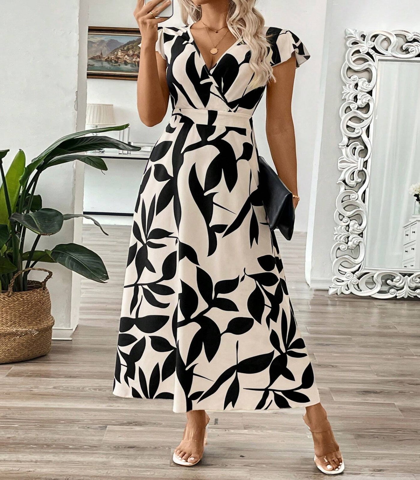 Woman wearing a black and white patterned dress in a room with decor elements.
