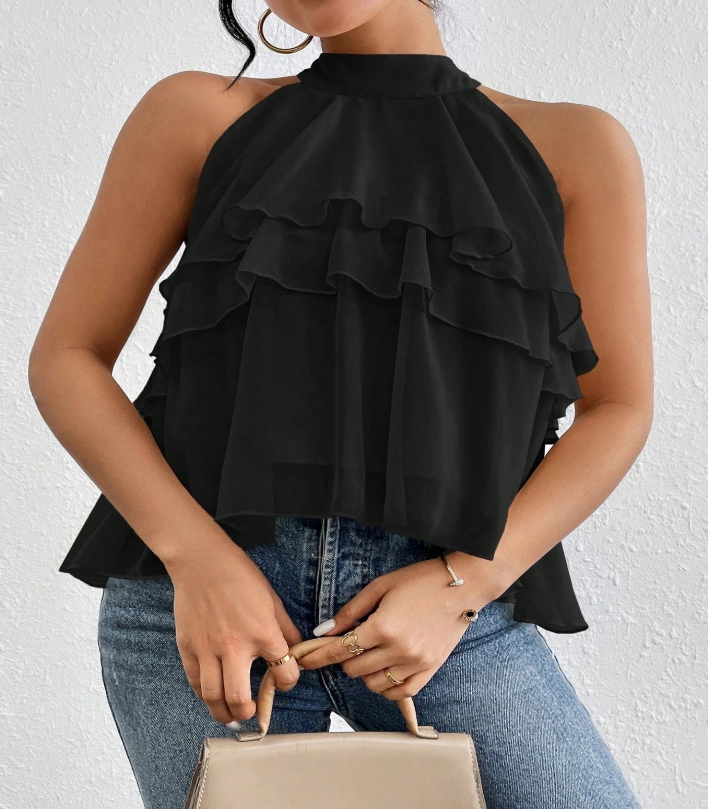 Black ruffled top worn by a person against a white background