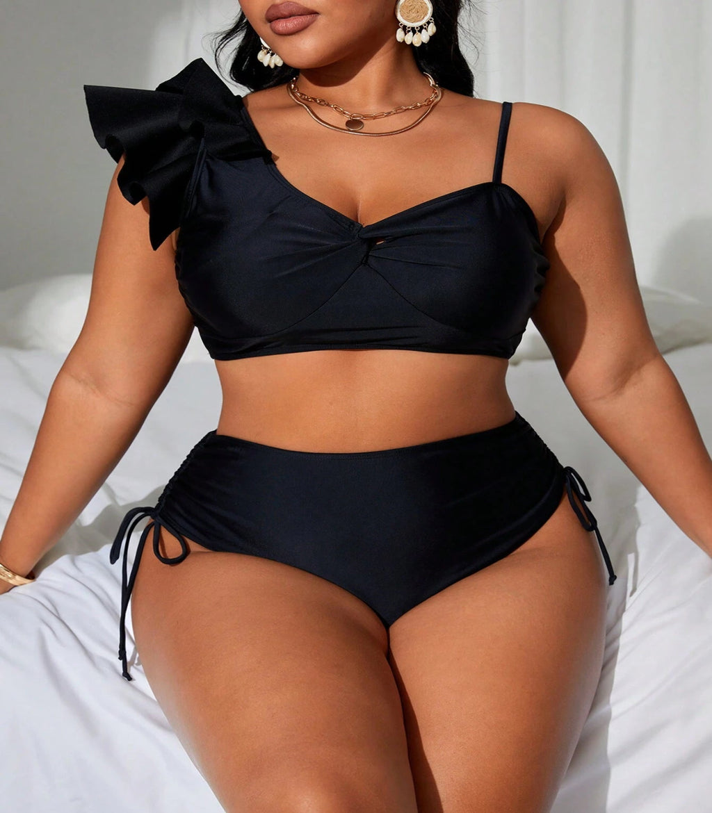 Woman wearing a black bikini with ruffled top and high-waisted bottoms on a white background