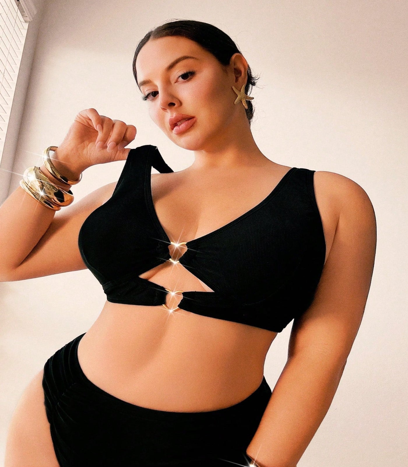 Woman wearing a black bikini top with cut-out design against a neutral background