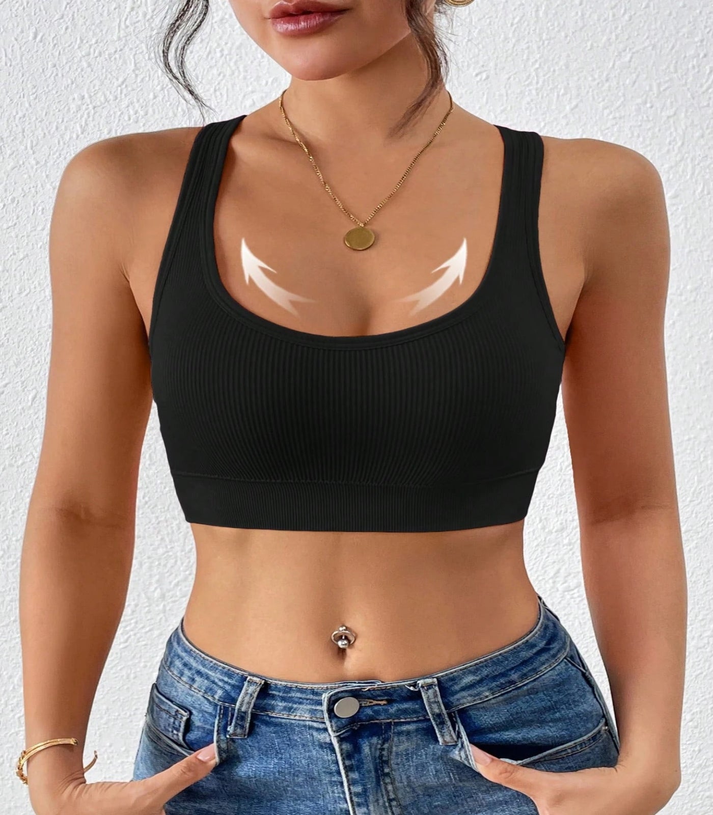 Person wearing a black sports bra and blue jeans against a white background