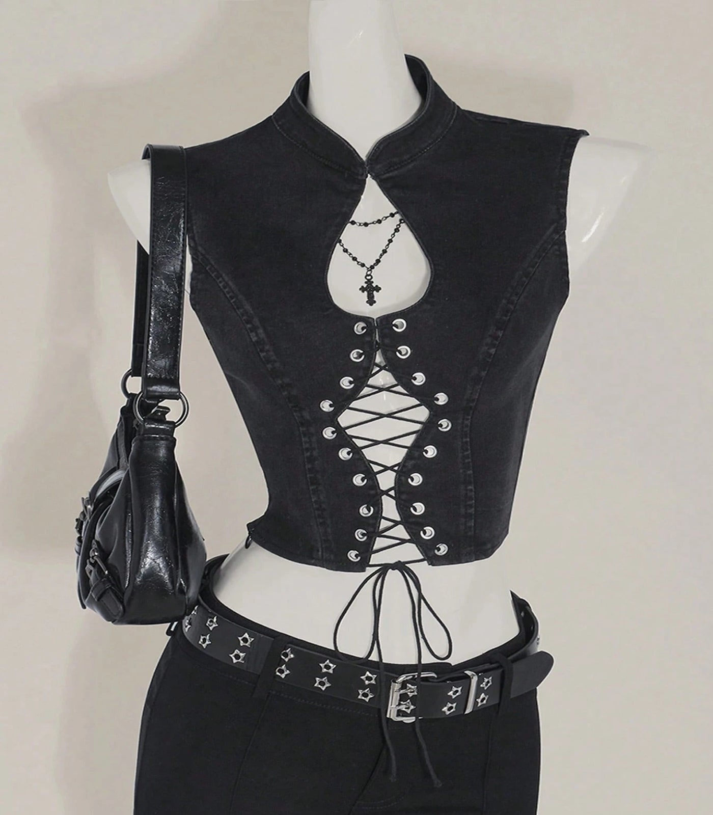 Black lace-up vest on a mannequin with a black handbag against a neutral background