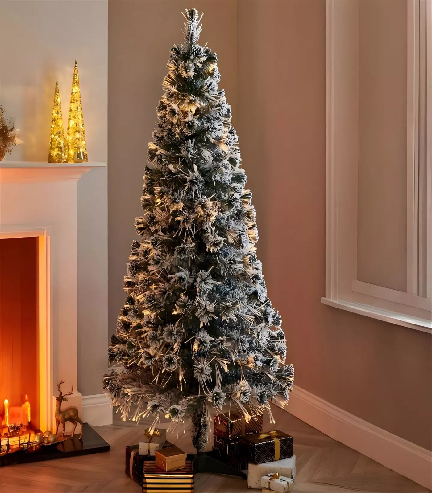 Decorated Christmas tree in a room with a fireplace and presents underneath.