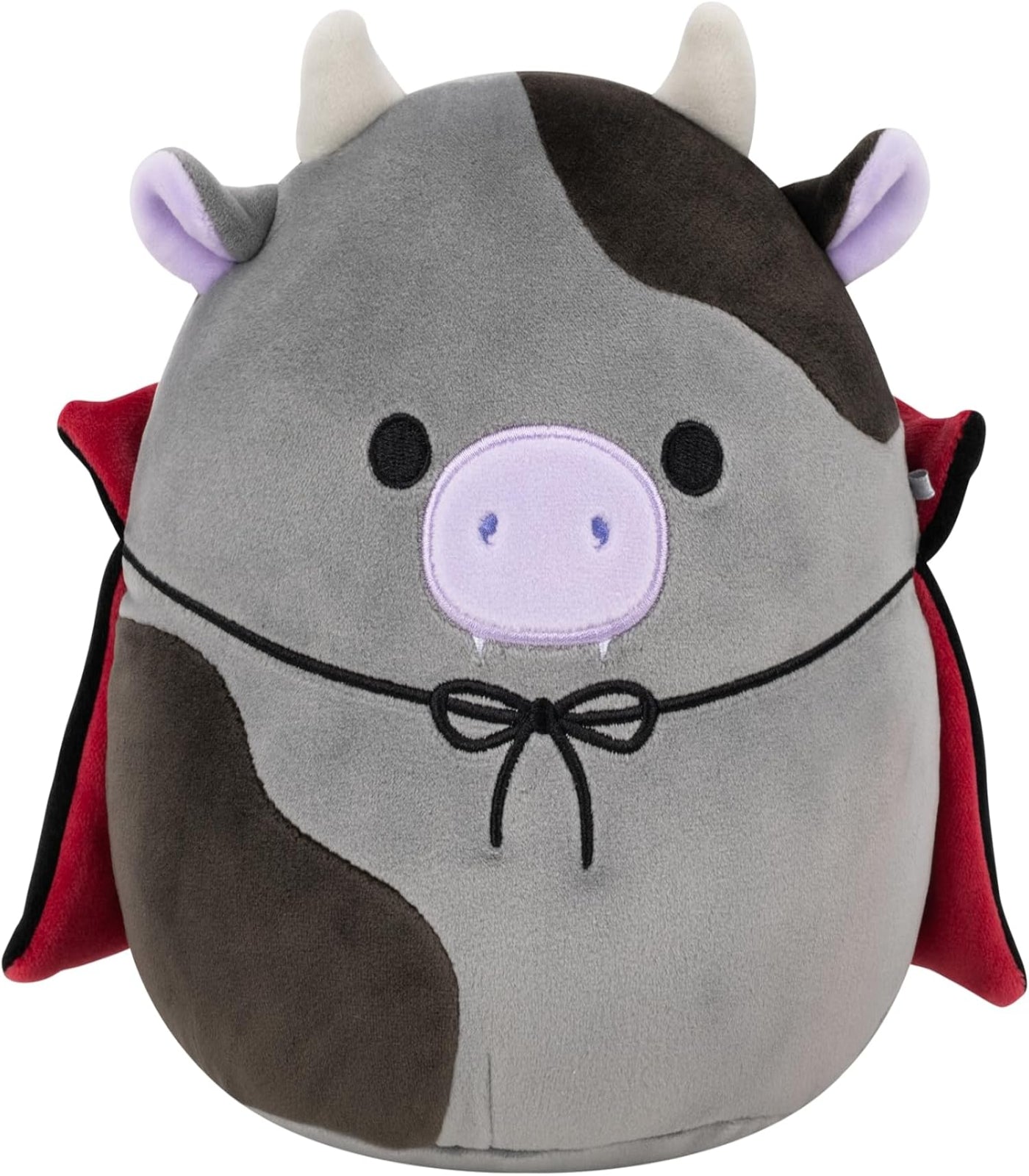Plush toy resembling a cow with devil horns, tail, and red cape on a white background