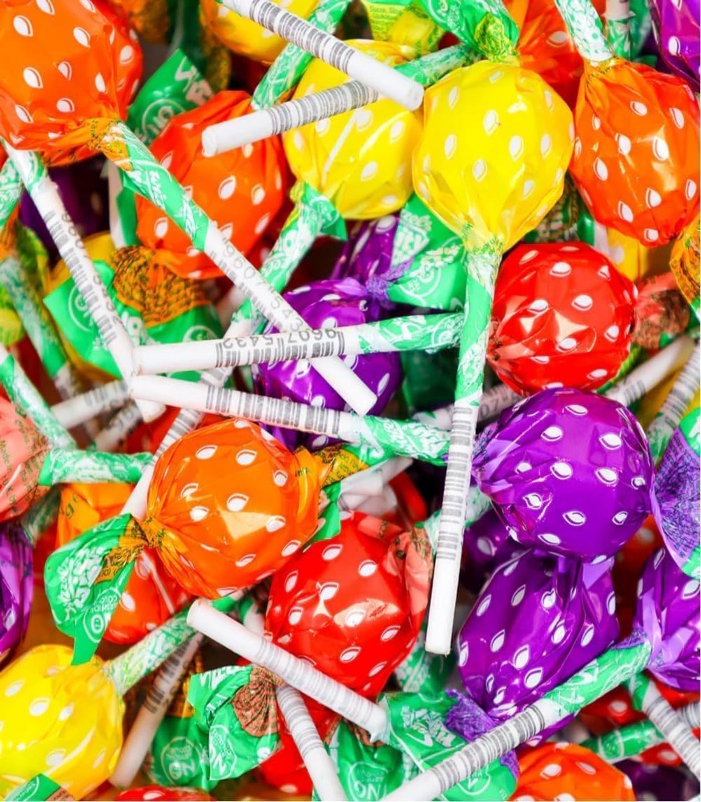 Assorted colorful lollipops with polka dot designs and white sticks.
