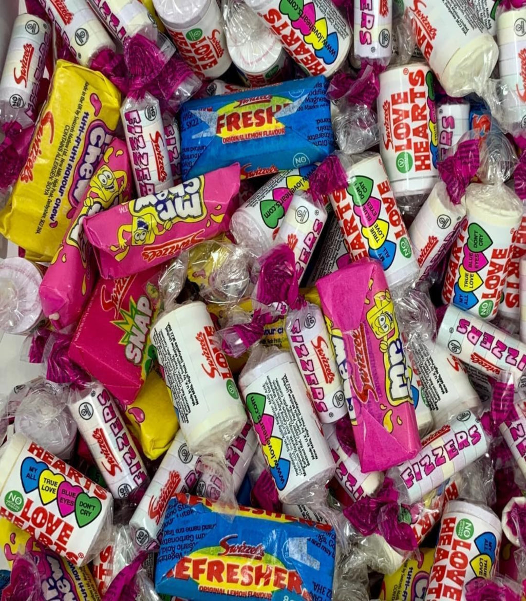 Assorted colorful candy bars including Love Hearts and Freddies in a pile.