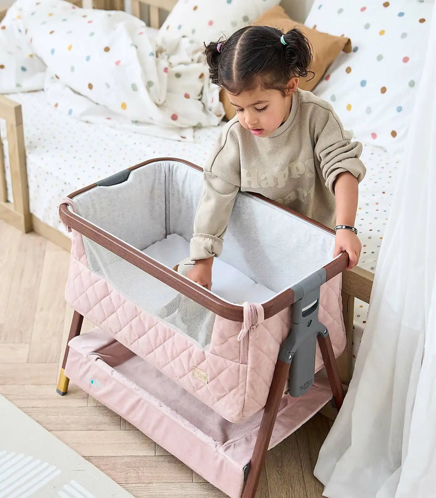 Child interacting with a portable crib in a bedroom setting