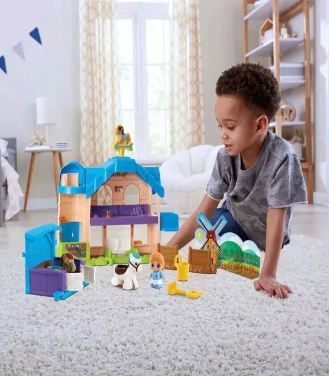 Child playing with toy house and figures on a carpeted floor